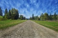 Travel road on the field with green grass and blue sky with clouds on the farm in beautiful summer sunny day. Clean, idyllic, land Royalty Free Stock Photo