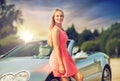 Happy young woman posing at convertible car