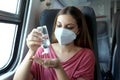 Travel safely on public transport. Young woman with KN95 FFP2 face mask using wash hand sanitizer gel dispenser. Passenger with Royalty Free Stock Photo