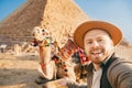 Travel selfie photo tourist man in hat with camel background pyramid of Egyptian Giza, sunset Cairo, Egypt Royalty Free Stock Photo
