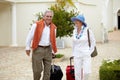 Travel, suitcase and elderly couple walking on vacation in a holiday location happy in retirement together by a hotel Royalty Free Stock Photo