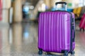 Travel suitcase positioned beside the entrance of a bustling and busy airport terminal