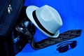 Travel-suitcase, sunglasses, tie and white hat on creative blue background. Travel to the tropical beach world of leisure or