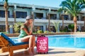 Travel, summer holidays and vacation concept - Beautiful woman walking near hotel pool area with red suitcase in Egypt