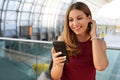 Travel and technology. Excited young woman receiving good news on her smartphone waiting for boarding in airport terminal Royalty Free Stock Photo