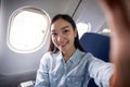 Travel and technology. Young woman asian in plane taking selfie while sitting in airplane seat