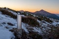 Travel thermos for hot drinks. Thermos on top of the mountain. Thermos, snow, stones and mountains. With a thermos outside Royalty Free Stock Photo