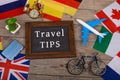 blackboard with text & x22;Travel TIPS& x22;, flags of different countries, airplane model, little bicycle and suitcase, com Royalty Free Stock Photo