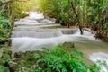 Travel to the beautiful waterfall in tropical rain forest, soft water of the stream in the natural park at Kanchanaburi, Thailand Royalty Free Stock Photo