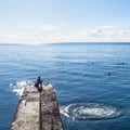 Fisher on pier and swimming tourists in Black Sea