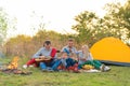 Travel, tourism, hike, picnic and people concept - group of happy friends with tent and drinks playing guitar at camping Royalty Free Stock Photo