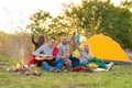 Travel, tourism, hike, picnic and people concept - group of happy friends with tent and drinks playing guitar at camping Royalty Free Stock Photo