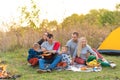 Travel, tourism, hike, picnic and people concept - group of happy friends with tent and drinks playing guitar at camping Royalty Free Stock Photo