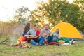 Travel, tourism, hike, picnic and people concept - group of happy friends with tent and drinks playing guitar at camping Royalty Free Stock Photo