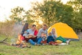 Travel, tourism, hike, picnic and people concept - group of happy friends with tent and drinks playing guitar at camping Royalty Free Stock Photo