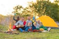 Travel, tourism, hike, picnic and people concept - group of happy friends with tent and drinks playing guitar at camping Royalty Free Stock Photo