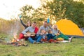 Travel, tourism, hike, picnic and people concept - group of happy friends with tent and drinks playing guitar at camping Royalty Free Stock Photo