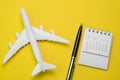 Travel, tourism, holiday or vacation planning concept, small white clean calendar with black pen and toy airplane on vibrant yell