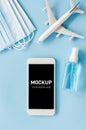 Travel and Tourism Planning after Quarantine. Mock up of smartphone with airplane model, face mask and sanitizer Royalty Free Stock Photo