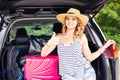 Travel, tourism - woman sitting in the trunk of a car with suitcases, showing thumb up sign, ready to leave for Royalty Free Stock Photo