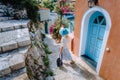 Travel tourist blonde woman with sun hat walking through narrow streets of an old greek town to the beach. Vacation Royalty Free Stock Photo