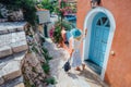 Travel tourist blonde woman with sun hat walking through narrow streets of an old greek town to the beach. Vacation Royalty Free Stock Photo