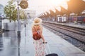 Travel by train, woman with luggage waiting on platform