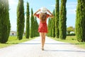 Travel in Tuscany. Young woman walking in beautiful and idyllic landscape of a lane of cypresses in the Tuscan countryside in