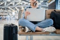 Travel vacation concept, asian female woman uses a smartphone and is working on a laptop, she sit wating for flight schedule at