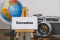Travel and vacation concept image,word RECREATION and with easel ,globe and vintage camera layout on wooden desk Royalty Free Stock Photo