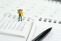 Travel, vacation or holiday calendar year plan concept, miniature traveller backpacker man figure standing on pile of calendars
