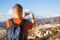 Travel, vacation, photographer and hitchhiker concept - raveler man photographed mountains and city in the smartphone