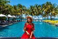 Travel vacation woman in red dress enjoying a summer vacation near swimming pool in tropical resort near the beach with Royalty Free Stock Photo