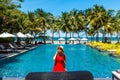 Travel vacation woman in red dress enjoying a summer vacation near swimming pool in tropical resort near the beach with Royalty Free Stock Photo