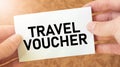 TRAVEL VOUCHER word inscription on white card paper sheet in hands of a businessman