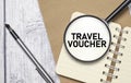 TRAVEL VOUCHER words on magnifying glass with pen and papers