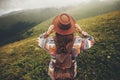 travel and wanderlust concept. stylish traveler hipster girl holding hat, with backpack and windy hair, walking in mountains in c