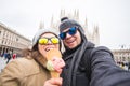 Travel in winter and Italy concept - Happy young couple take selfie photo with ice-cream in front of Milan Duomo Royalty Free Stock Photo