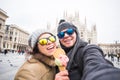 Travel in winter and Italy concept - Happy young couple take selfie photo with ice-cream in front of Milan Duomo Royalty Free Stock Photo