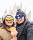 Travel in winter and Italy concept - Happy young couple take selfie photo with ice-cream in front of Milan Duomo Royalty Free Stock Photo