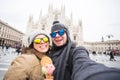 Travel in winter and Italy concept - Happy young couple take selfie photo with ice-cream in front of Milan Duomo Royalty Free Stock Photo