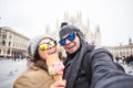 Travel in winter and Italy concept - Happy young couple take selfie photo with ice-cream in front of Milan Duomo Royalty Free Stock Photo