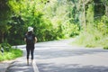 Travel woman with hat and backpack walking on a road Royalty Free Stock Photo