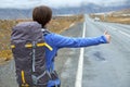 Travel woman hitchhiking. Beautiful young female hitchhiker by the road during vacation trip in mountains Royalty Free Stock Photo