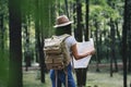 Travel woman reading map among trees at forest and searching directional for travling with a backpack Royalty Free Stock Photo