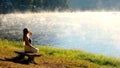 Travel woman relax on nature near misty lake. Female traveler sitting on bench