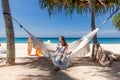 Travel Woman Sitting on White Hammock on Sandy Beach with Sea and Tropical Trees Royalty Free Stock Photo