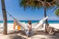 Travel Woman Sitting on White Hammock on Sandy Beach with Sea and Tropical Trees Royalty Free Stock Photo