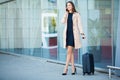 Travel. Young woman goes at airport at window with suitcase waiting for plane