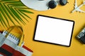 Traveler accessories, tropical palm leaf branches and digital tablet on yellow background.